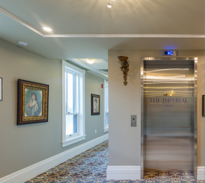 Exterior of a steel elevator in a hallway with beige wallpaper